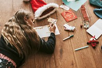 Kids writing Christmas cards on wooden floor