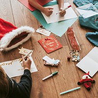 Kids writing Christmas cards on wooden floor