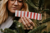 Happy woman wrapping up the tip of a Christmas tree at a Christmas tree farm 