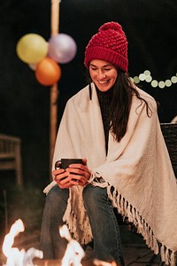 Woman keeping warm with hot chocolate, a beanie, and a shawl 