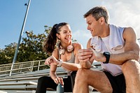 Athletic man and woman sitting down and talking by the stadium