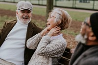 Old friends laughing together on park bench 