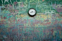 Messy scribbles on a wall and a clock.