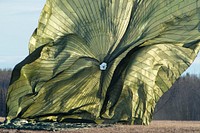 A heavy pallet parachute collapses after being deployed from a U.S. Air Force C-17-Globemaster III operated by the 517th Airlift Squadron during airborne training at Malemute Drop Zone Joint Base Elmendorf-Richardson, Alaska, April 30, 2019. Following a heavy equipment drop, paratroopers from 2nd Battalion, 377th Parachute Field Artillery Regiment, 4th Infantry Brigade Combat (Airborne), 25th Infantry Division, U.S. Army Alaska, conducted a parachute assault and honed their skills by setting up a M119A2 105 mm howitzer. (U.S. Air Force photo by Alejandro Peña). Original public domain image from Flickr