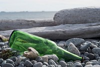 Glass bottle on shore. Original public domain image from Flickr