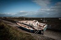 Abandoned rusting sailboat on shore. Original public domain image from Flickr