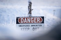 A sign warning of unexploded ammunition is seen covered in hoar frost as paratroopers assigned to the 2nd Battalion, 377th Parachute Field Artillery Regiment, 4th Infantry Brigade Combat Team (Airborne), 25th Infantry Division, U.S. Army Alaska, use M240B, and M2 machine guns while conducting live-fire qualification at Grezelka range, on Joint Base Elmendorf-Richardson, Alaska, Dec. 5, 2019. The Soldiers practiced identifying, and engaging targets at varying distances to solidify their proficiency with the weapons in sub-arctic conditions. (U.S. Air Force photo/Justin Connaher). Original public domain image from Flickr
