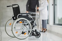 Close up of wheelchair with blur view of patient and doctor in the background, free public domain CC0 photo.