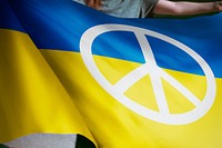 Person holding Ukraine flag with peace sign 