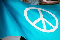 Person waving light blue flag with peace sign
