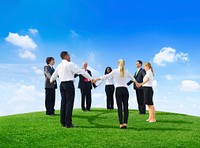 Business people holding hands on hill
