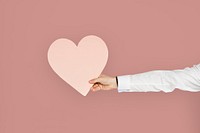 Hand holding a pink heart cutout, healthy heart or love concept