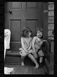 Small girls sitting in doorway of house in Georgetown, Washington, D.C.. Sourced from the Library of Congress.