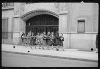 [Schoolgirls walking along street in front of Straubenmuller Textile High School, New York, New York]. Sourced from the Library of Congress.