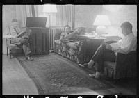 Washington, D.C. The room of a government clerk(?), showing three young men reading and listening to a radio in the evening. Sourced from the Library of Congress.