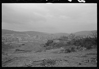 [Mount Carmel,] Pennsylvania. A bird's-eye view of the town showing two sections, one showing big buildings and numerous church spires, and the other, rows of homes, connected by a bridge. Coalyards on the outskirts fill the foreground, and hills loom above the village, in the background of the picture. Sourced from the Library of Congress.