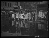Washington, D.C. People on a rainy night at 13th Street and F Street, N.W. waiting for the "Don't walk" neon traffic light to signal "Walk". Sourced from the Library of Congress.