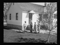E.O. Stenquist, his wife, and one of their children talk with RR (Rural Rehabilitation) supervisor Glenn F. Cowan in front of the completely remodeled family home which is one result of the Farm Security Administration tenant purchase loan made to Stenquist in 1939. After one season's operations under the loan, this farmer was selected by Utah Farm Security Administration supervisors as the government program's most successful farmer of 1939. Sourced from the Library of Congress.