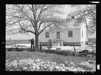 The Marvin R. Jeppesen family does some spring cleaning in front of the home built with part of their tenant purchase loan. This family is making a success on the first farm they have been able to own. In Box Elder County, Utah. Sourced from the Library of Congress.
