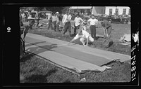 Firemen's muster. Boothbay center, Maine. Measuring the farthest drop of water on building paper which is unrolled fresh for each team. Distances were in the neighborhood of two hundred feet. Sourced from the Library of Congress.