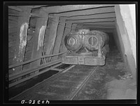 Shenandoah (vicinity), Pennsylvania. A compressed air engine approaching with a train of cars in the Maple Hill mine. The pipes beside the track carry eight hundred pounds and there are valves for refueling every quarter mile. Compressed air is piped down from the surface. Sourced from the Library of Congress.