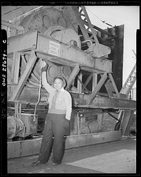 One of the 1,000 skilled  women working at the Kaiser shipyards, at Richmond, California, who helped build the SS George Washington Carver, launched on May 7, 1943. Miss Odie Mae Embry mans the emergency switch for the protection of track workers as the huge crane swings 100 feet above. Sourced from the Library of Congress.