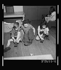 New York, New York. Children of the nursery school group at Greenwich House putting on their shoes after a rest period which is a part of the educational recreation program offered by this neighborhood center for working mothers' children. Sourced from the Library of Congress.