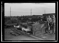 Boston and Maine railroad shops at Billerica, Massachusetts. Open air furnaces melting the lead from the huge locomotive driving wheels. The lead dripping can be senn being caught. Sourced from the Library of Congress.