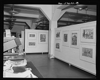 Installation of the United States Office of War Information (OWI) exhibit of original drawings and paintings by artists now in the armed forces. Preview, before shipping to Australia, held at the office of the Overseas Picture Division in the Auditor's Building. Sourced from the Library of Congress.