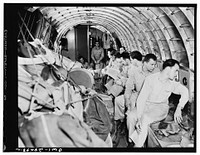 United States Air Transport Command cargo planes do double duty in transporting both cargo and personnel. The cargo is piled against the sides of the ship and there lashed in place. These are fighter pilots being flown on the same plane to join a squadron. Sourced from the Library of Congress.