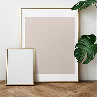Gold photo frame by the houseplant on a wooden floor