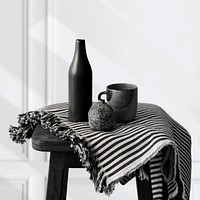 Black ceramic vase with a mug on a wooden stool 