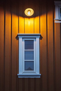 Outdoor lamp above a window in a yellow cabin on Lofoten island, Norway 