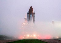 KENNEDY SPACE CENTER, FLA. the fog on Launch Pad 39B is pierced by lights on vehicles and the service structures as Space Shuttle Atlantis approaches.