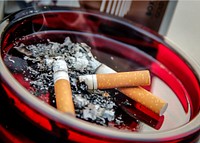 A ruby&ndash;colored glass ashtray contained three used cigarette butts along with their ashes.