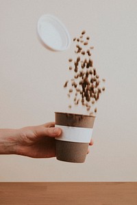 Hand shaking coffee beans in a cork coffee cup
