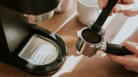 Barista pressing ground coffee in a coffee machine filter
