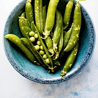 Fresh organic peas in a blue cup