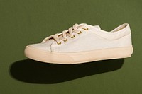 Unisex cream colored sneakers on an olive green background 