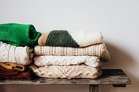 Folded winter sweaters on a wooden shelf 