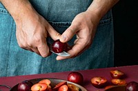 Man cutting red plums in a kitchen