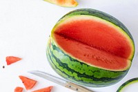 Watermelon with knife on white table