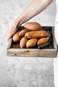 Woman with sweet potatoes in wooden box