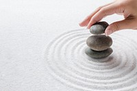 Hand stacking zen stones on the sand wellness background