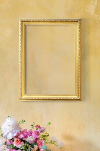 Golden frame on a yellow wall by flowers