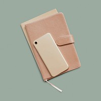 Mobile phone and a notebook on a sage green background