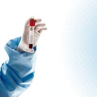 Hand wearing glove holding blood sample in tube test