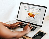 Woman reading coronavirus updates from a laptop mockup with editorial graphic from <a href="https://www.cdc.gov/coronavirus/2019-ncov/cases-updates/cases-in-us.html">https://www.cdc.gov/coronavirus/2019-ncov/cases-updates/cases-in-us.html</a> accessed on April 8th 2020. LOS ANGELES, USA- MARCH 27, 2019<br /><br /> 