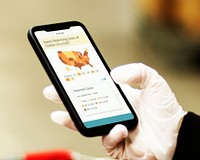 Woman wearing sanitary gloves reading coronavirus updates from a mobile phone mockup with editorial graphic from <a href="https://www.cdc.gov/coronavirus/2019-ncov/cases-updates/cases-in-us.html">https://www.cdc.gov/coronavirus/2019-ncov/cases-updates/cases-in-us.html</a> accessed on April 8th 2020. BANGKOK, THAILAND - MARCH 24, 2020