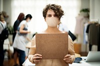 Woman wearing mask holding a blank placard new normal